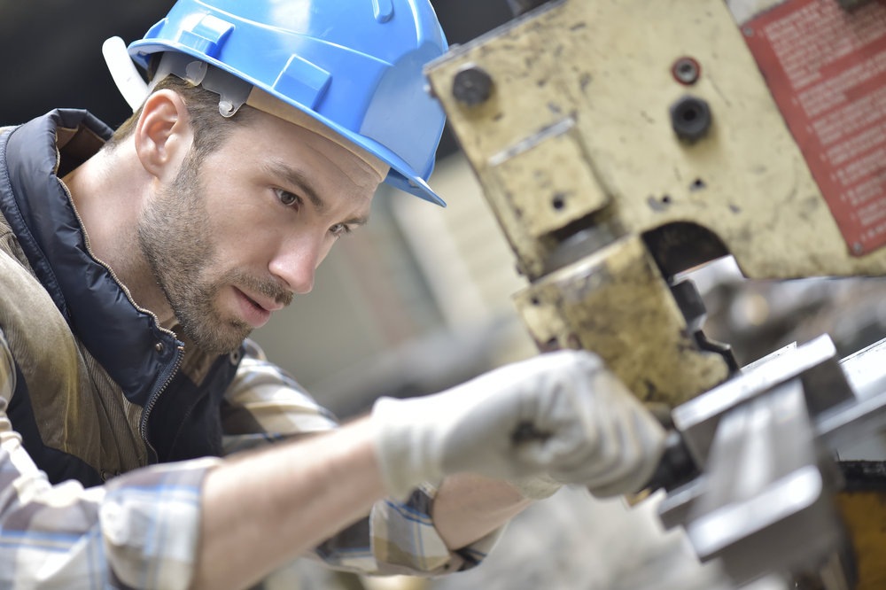 Industrial worker working on machine in factory