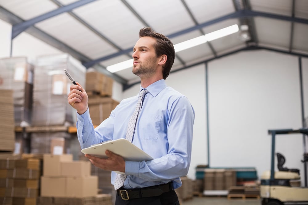 Side view of manager holding clipboard in the warehouse